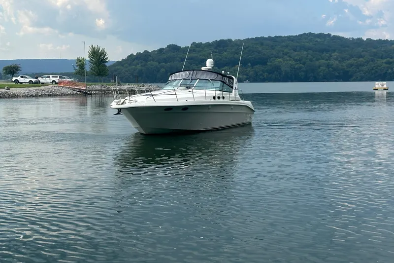 Slide: The Image of 1997 Sea Ray 400 Express Cruiser on a calm lake with scenic background. - 3