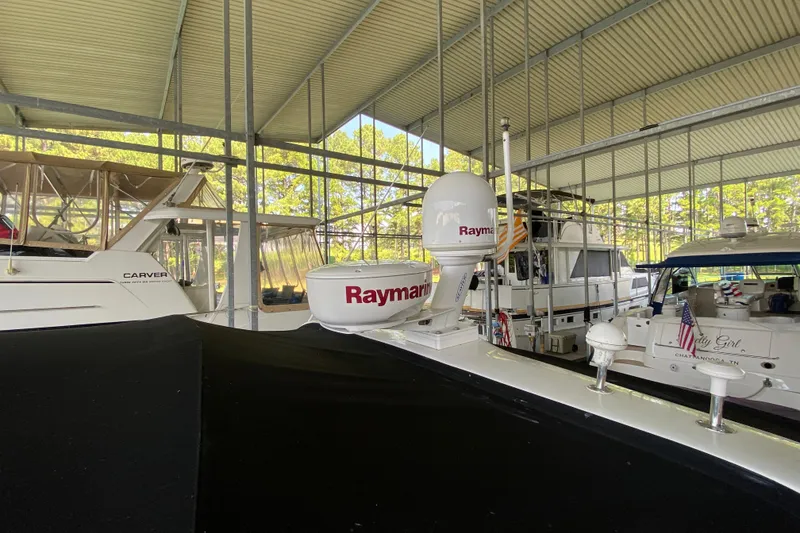 Slide: The Image of 1997 Sea Ray 400 Express Cruiser docked in a covered marina with other boats. - 31