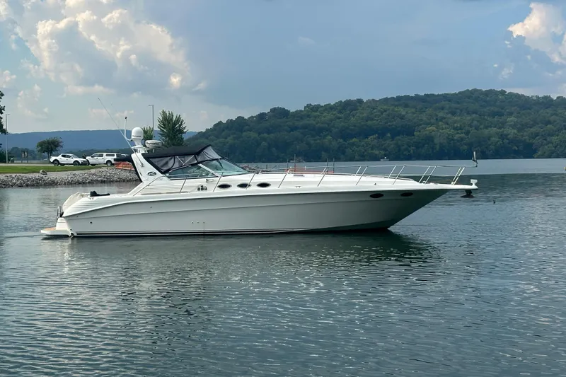 Slide: The Image of 1997 Sea Ray 400 Express Cruiser on a serene lake with lush green hills. - 4