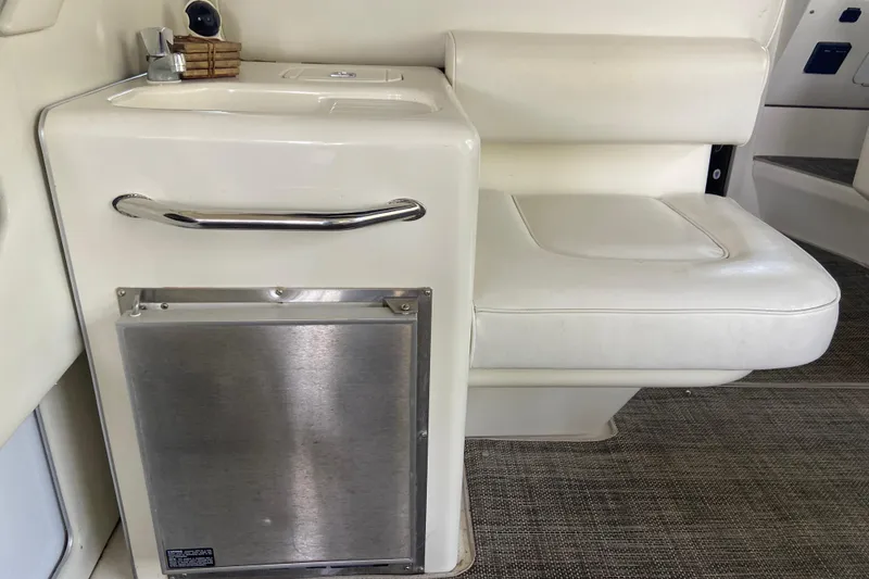 Slide: The Image of 1997 Sea Ray 400 Express Cruiser interior with white seating and compact kitchenette. - 9