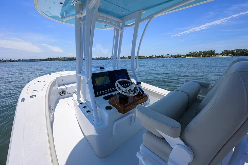 Slide: The Image of 2024 Conch 25 boat interior with helm, steering wheel, and seating on calm water. - 12