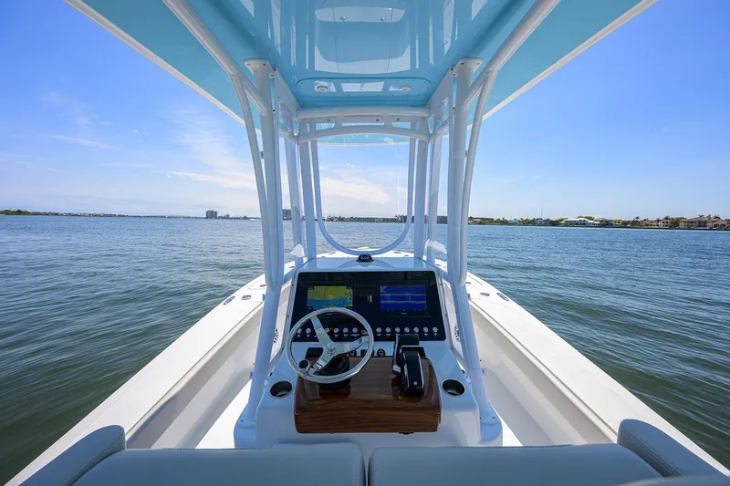 Slide: The Image of 2024 Conch 25 boat dashboard with steering wheel, on open water under clear blue sky. - 14