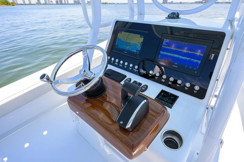 Slide: The Image of 2024 Conch 25 boat dashboard with navigation screens and steering wheel on calm water. - 15