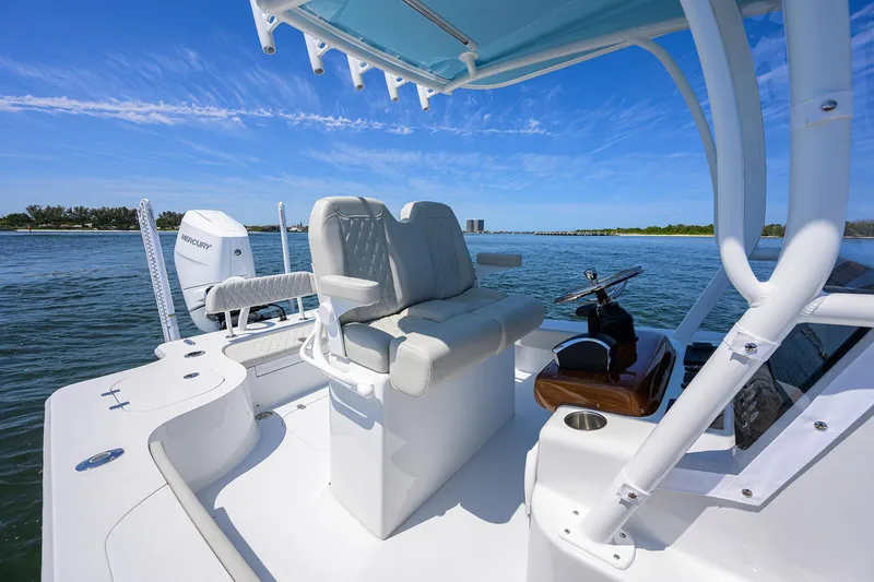 Slide: The Image of 2024 Conch 25 boat interior with seating and steering, on a sunny day by the water. - 17
