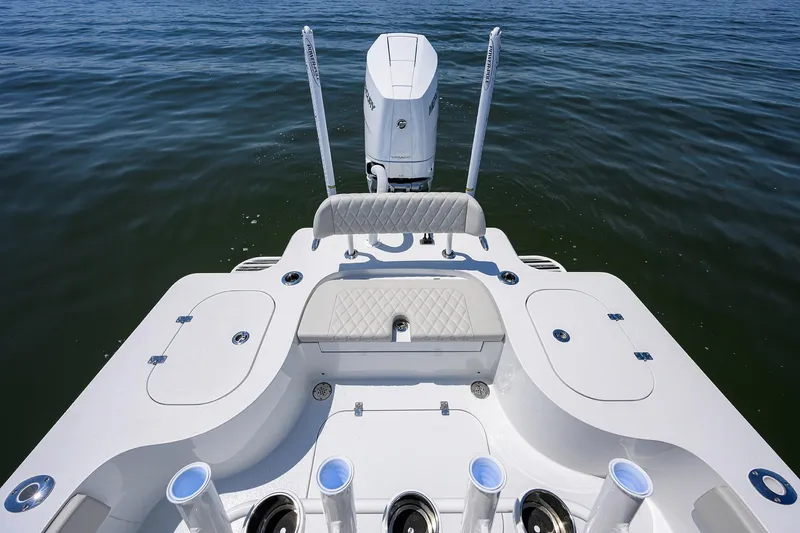 Slide: The Image of 2024 Conch 25 boat deck with motor, rod holders, and seating on calm water. - 23