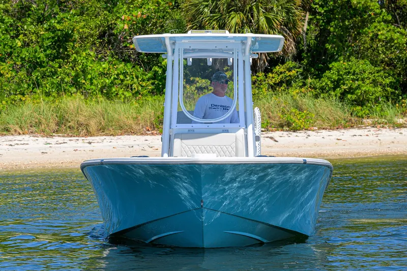 Slide: The Image of 2024 Conch 25 boat on water near a sandy beach with lush greenery. - 3