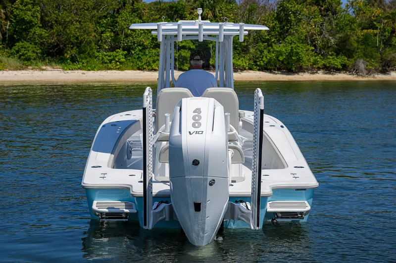 Slide: The Image of 2024 Conch 25 boat with powerful V10 engine, cruising on calm water near a lush shoreline. - 34