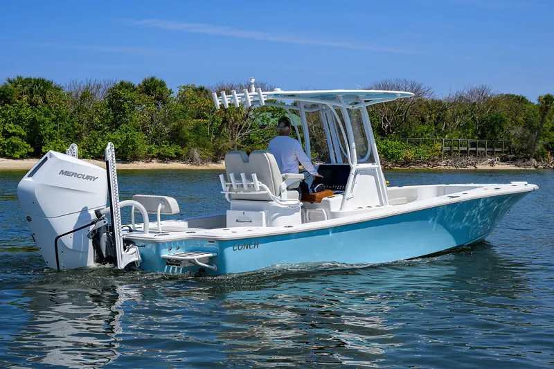 Slide: The Image of 2024 Conch 25 boat cruising on water with Mercury engine, clear sky, and lush shoreline. - 35