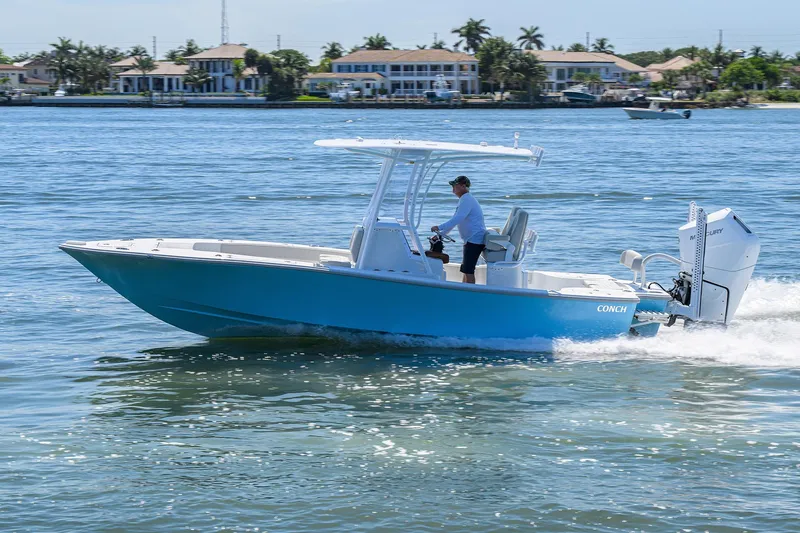 Slide: The Image of 2024 Conch 25 boat cruising on a sunny day near waterfront homes. - 38