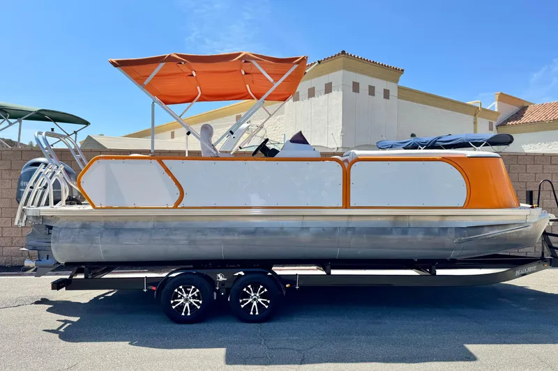 The Image of 2022 Aloha Pontoon 230 with orange canopy on trailer, parked outdoors. - 0