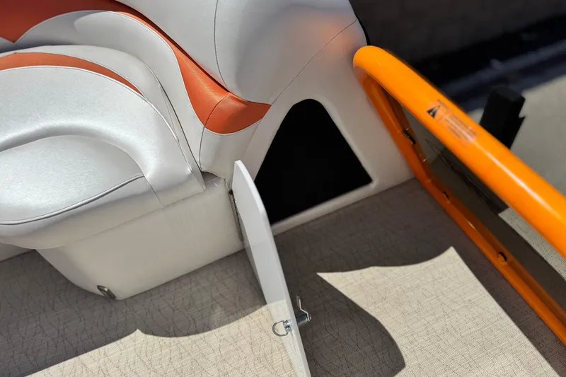 Slide: The Image of 2022 Aloha Pontoon 230 interior with white and orange seating, open storage compartment. - 12