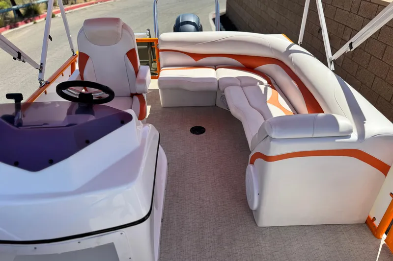 Slide: The Image of 2022 Aloha Pontoon 230 interior with white and orange seating, steering console, and spacious layout. - 13