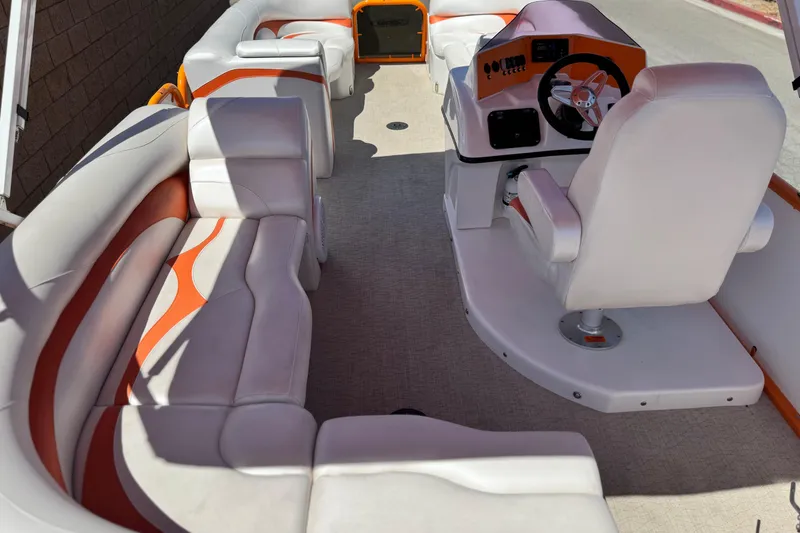 Slide: The Image of 2022 Aloha Pontoon 230 interior with white and orange seating, steering console, and spacious layout. - 18