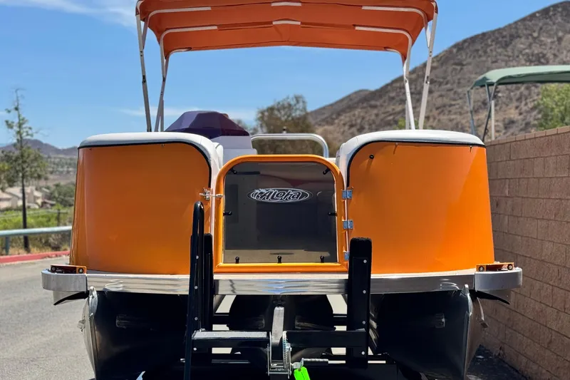 Slide: The Image of 2022 Aloha Pontoon 230 with orange canopy, parked on a sunny day. - 2