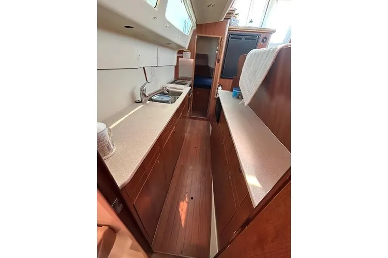 Slide: The Image of Interior of 2013 Gemini Legacy boat featuring a compact kitchen with wooden cabinetry. - 22