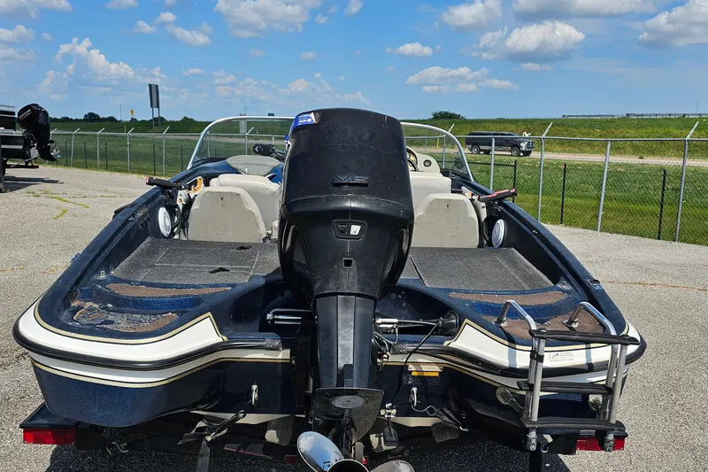 Slide: The Image of 2004 ProCraft 180 Combo boat with outboard motor, parked on pavement under a blue sky. - 3