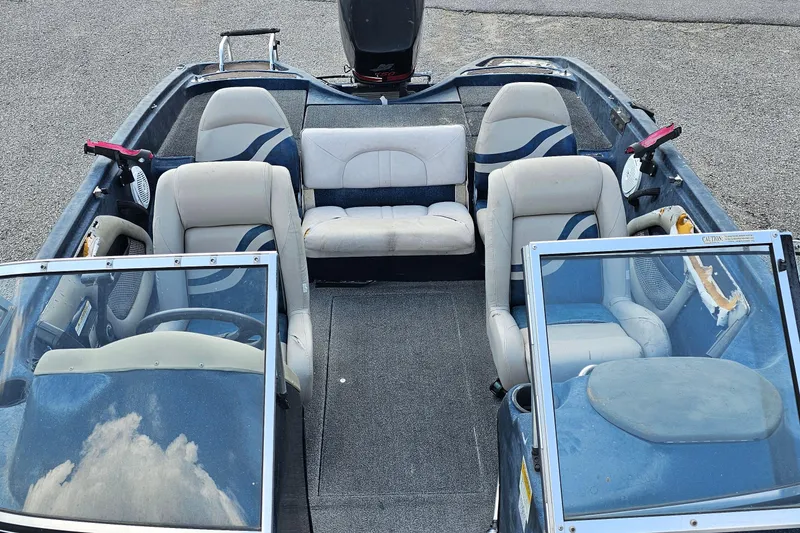 Slide: The Image of 2004 ProCraft 180 Combo boat interior with seating and steering wheel, parked on pavement. - 7