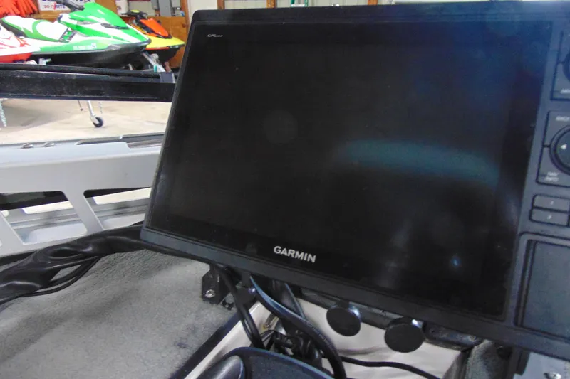 Slide: The Image of Garmin GPS unit on 2005 Triton Tr-196 PD boat dashboard, with jet skis in background. - 10