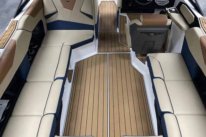 Slide: The Image of 2025 Nautique Super Air Nautique S23 interior with beige and blue seating, wood-style flooring. - 3