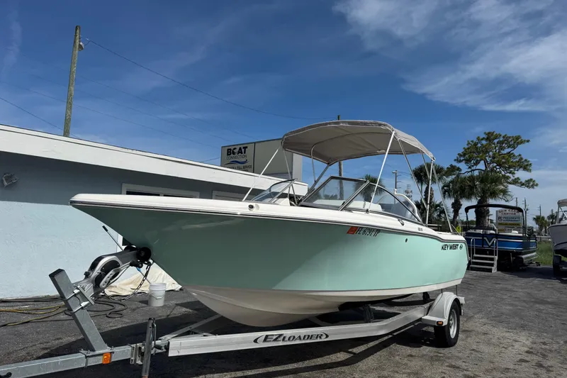 Slide: The Image of 2023 Key West 203 DFS boat on trailer, parked outdoors under clear sky. - 2
