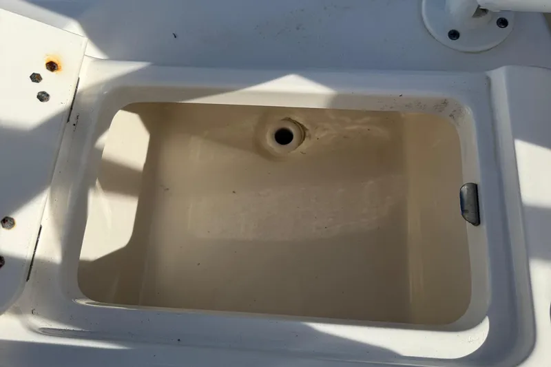 Slide: The Image of 2023 Key West 203 DFS boat storage compartment with drain, showing rusted screws. - 31