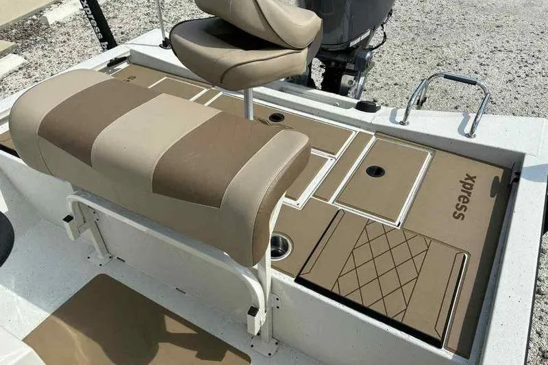 Slide: The Image of 2026 Xpress H210B boat interior with tan seating and storage compartments. - 11
