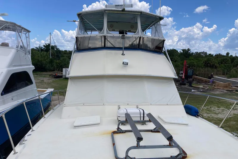 Slide: The Image of 1985 Hatteras Sportfish boat docked, featuring a spacious deck and enclosed flybridge. - 16