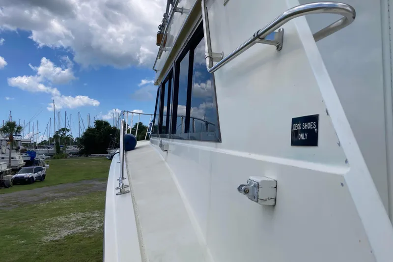 Slide: The Image of 1985 Hatteras Sportfish boat with "Deck Shoes Only" sign, docked under a cloudy sky. - 19