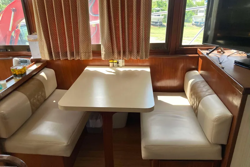 Slide: The Image of 1985 Hatteras Sportfish interior with dining booth, wood paneling, and large windows. - 25