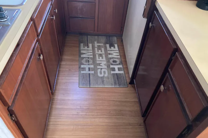 Slide: The Image of 1985 Hatteras Sportfish kitchen with wooden cabinets and "Home Sweet Home" mat. - 29