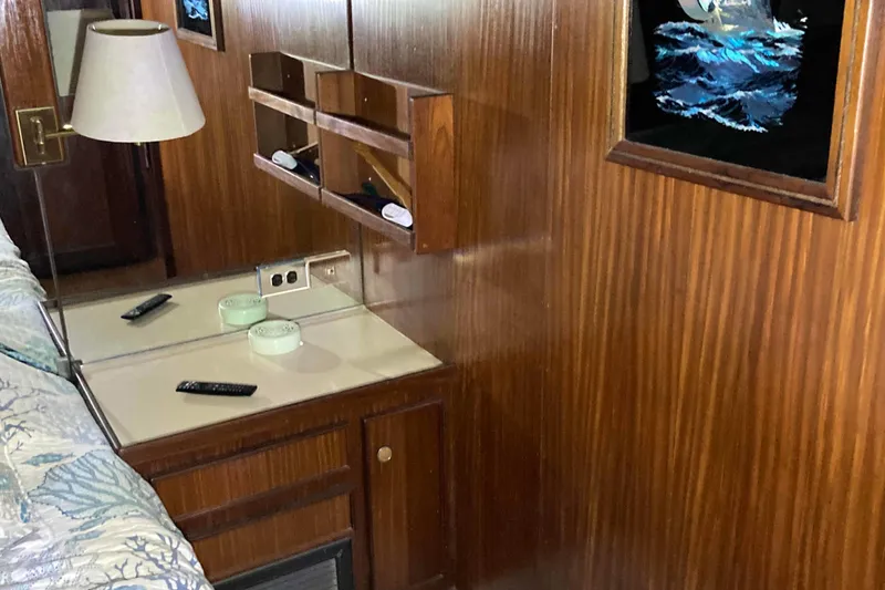 Slide: The Image of 1985 Hatteras Sportfish interior with wood paneling, desk, and wall art. - 32
