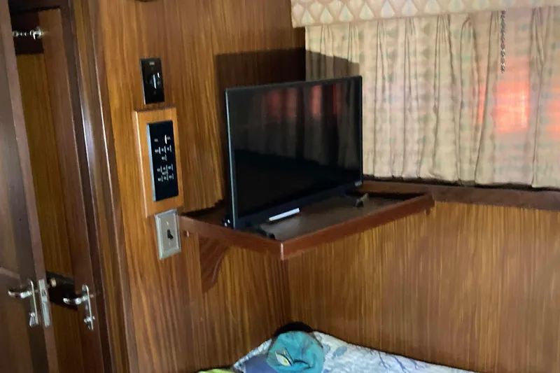 Slide: The Image of 1985 Hatteras Sportfish cabin interior with TV, wood paneling, and curtains. - 33