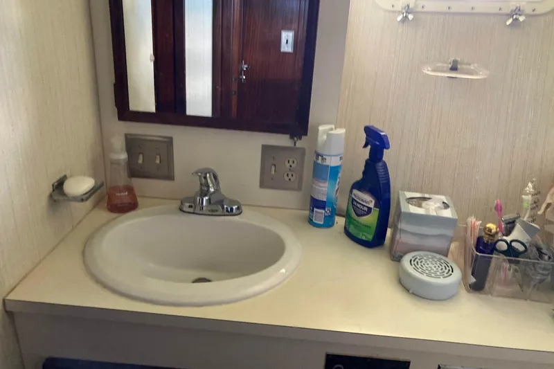 Slide: The Image of Bathroom sink area on a 1985 Hatteras Sportfish yacht with toiletries and cleaning supplies. - 38