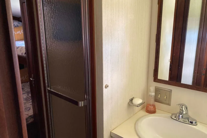 Slide: The Image of 1985 Hatteras Sportfish bathroom with sink, mirror, and shower door. - 39