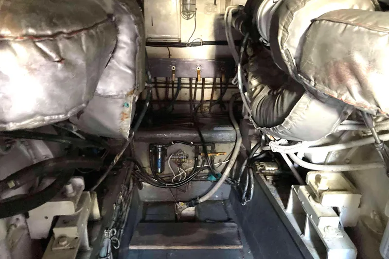 Slide: The Image of Engine room of a 1985 Hatteras Sportfish boat, showcasing mechanical components and wiring. - 44