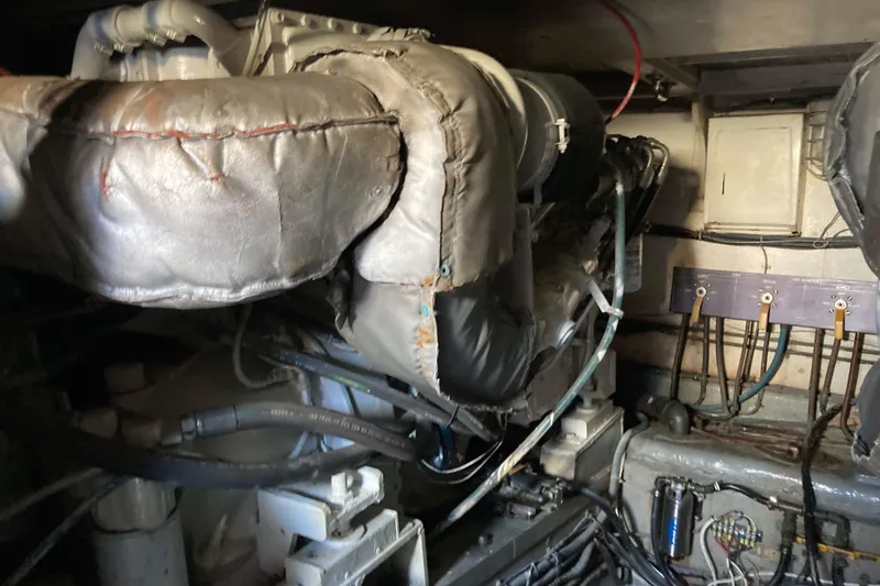 Slide: The Image of Engine room of a 1985 Hatteras Sportfish boat, showcasing mechanical components and wiring. - 45