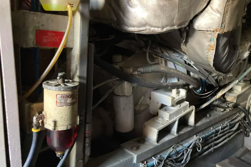 Slide: The Image of Engine compartment of a 1985 Hatteras Sportfish boat, showing mechanical components and hoses. - 46