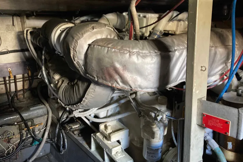 Slide: The Image of Engine room of a 1985 Hatteras Sportfish boat, showcasing complex machinery and wiring. - 47