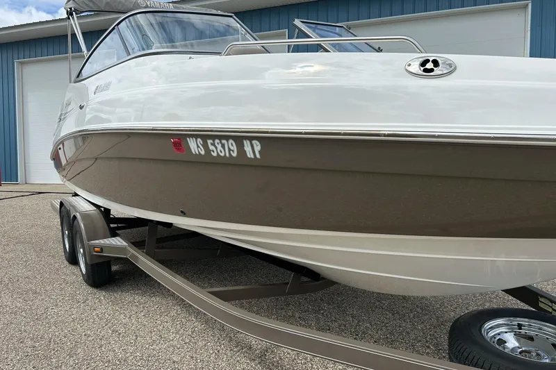 Slide: The Image of 2008 Searay SX 232 boat on trailer, parked outside blue building. - 3