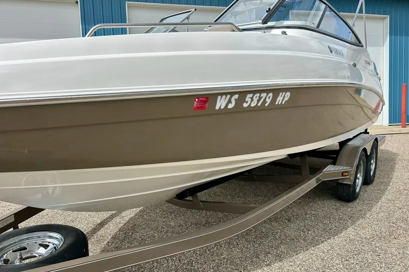 Slide: The Image of 2008 Searay SX 232 boat on trailer, parked outside a blue building. - 40