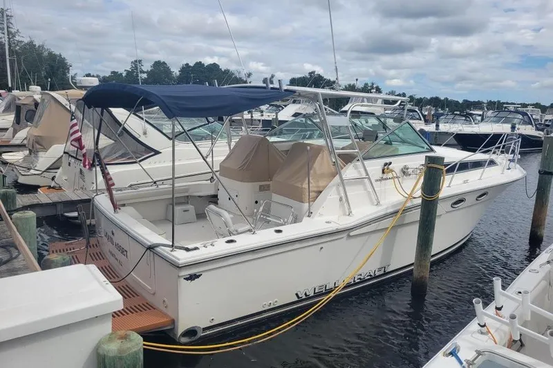 Slide: The Image of 1997 Wellcraft 330 Coastal boat docked at marina under cloudy sky. - 0