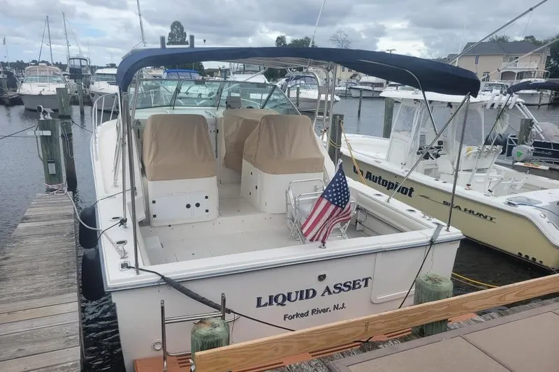 Slide: The Image of 1997 Wellcraft 330 Coastal boat docked, featuring covered seats and American flag. - 1