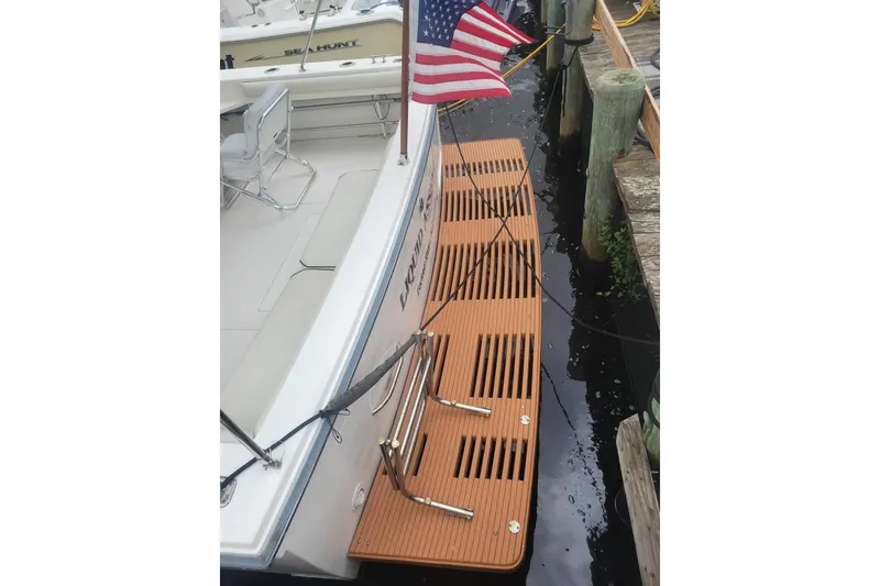 Slide: The Image of 1997 Wellcraft 330 Coastal boat docked with American flag and wooden swim platform. - 4