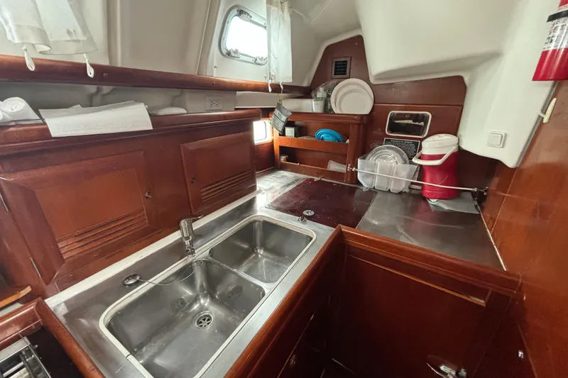 Slide: The Image of Galley kitchen of 2004 Beneteau Oceanis 423 sailboat with wooden cabinetry and stainless steel sink. - 20