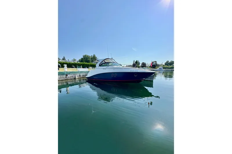 Slide: The Image of 2015 Rinker 340 Express Cruiser docked on calm water under clear blue sky. - 1
