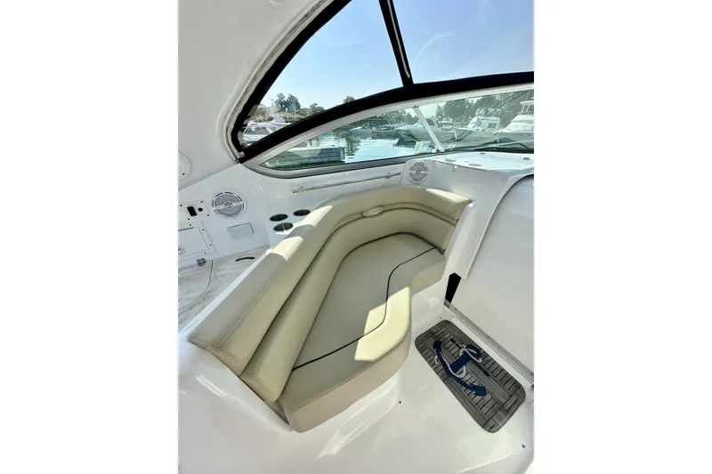 Slide: The Image of 2015 Rinker 340 Express Cruiser interior with beige seating and window view. - 10