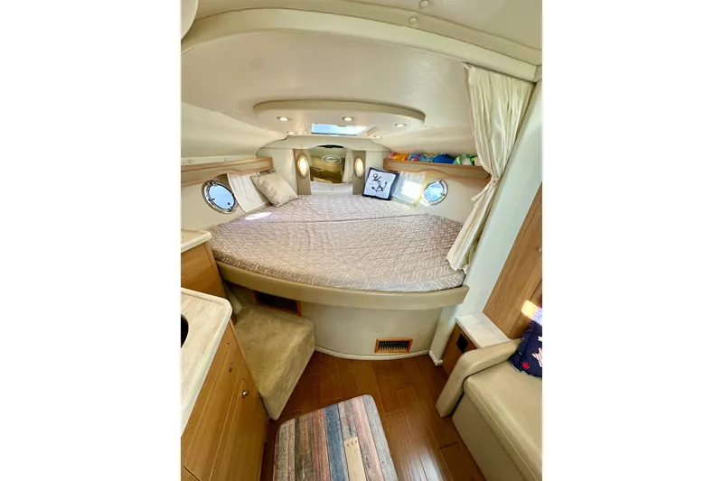 Slide: The Image of 2015 Rinker 340 Express Cruiser cabin interior with cozy bed and wooden furnishings. - 21