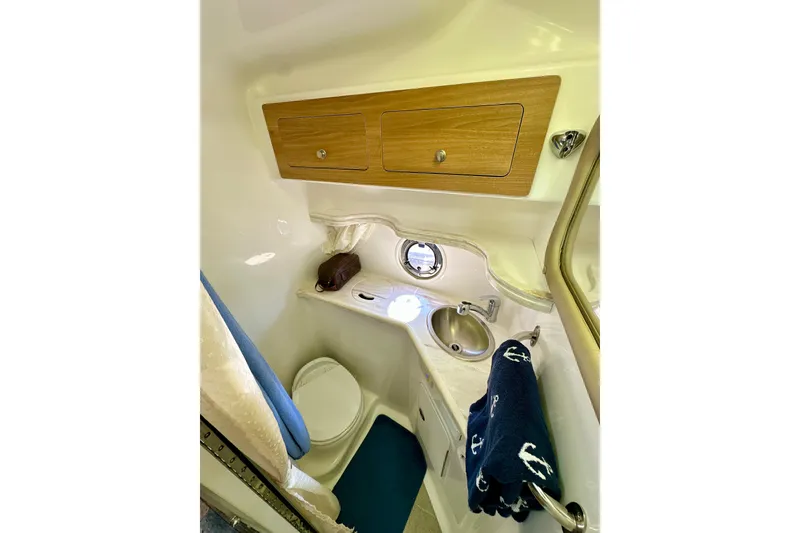 Slide: The Image of 2015 Rinker 340 Express Cruiser bathroom with sink, toilet, and wooden cabinets. - 25