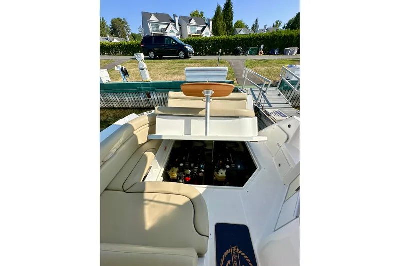 Slide: The Image of 2015 Rinker 340 Express Cruiser interior with open engine compartment, docked near residential area. - 30