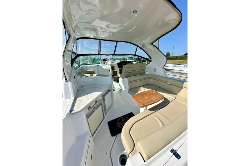 Slide: The Image of 2015 Rinker 340 Express Cruiser interior with beige seating and wooden table. - 5